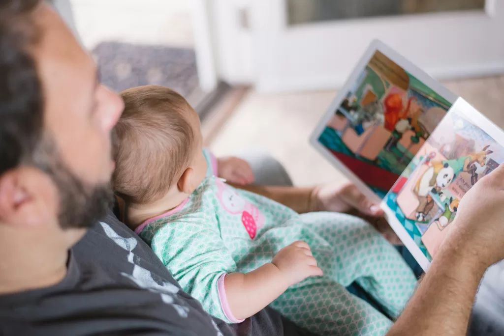 Single Parent Dad reading to baby on his knee