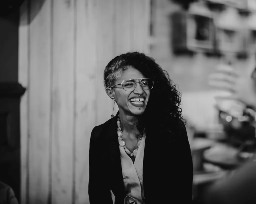 A black and white photo of Natalia-Nana Lester-Bush smiling and wearing a black jacket